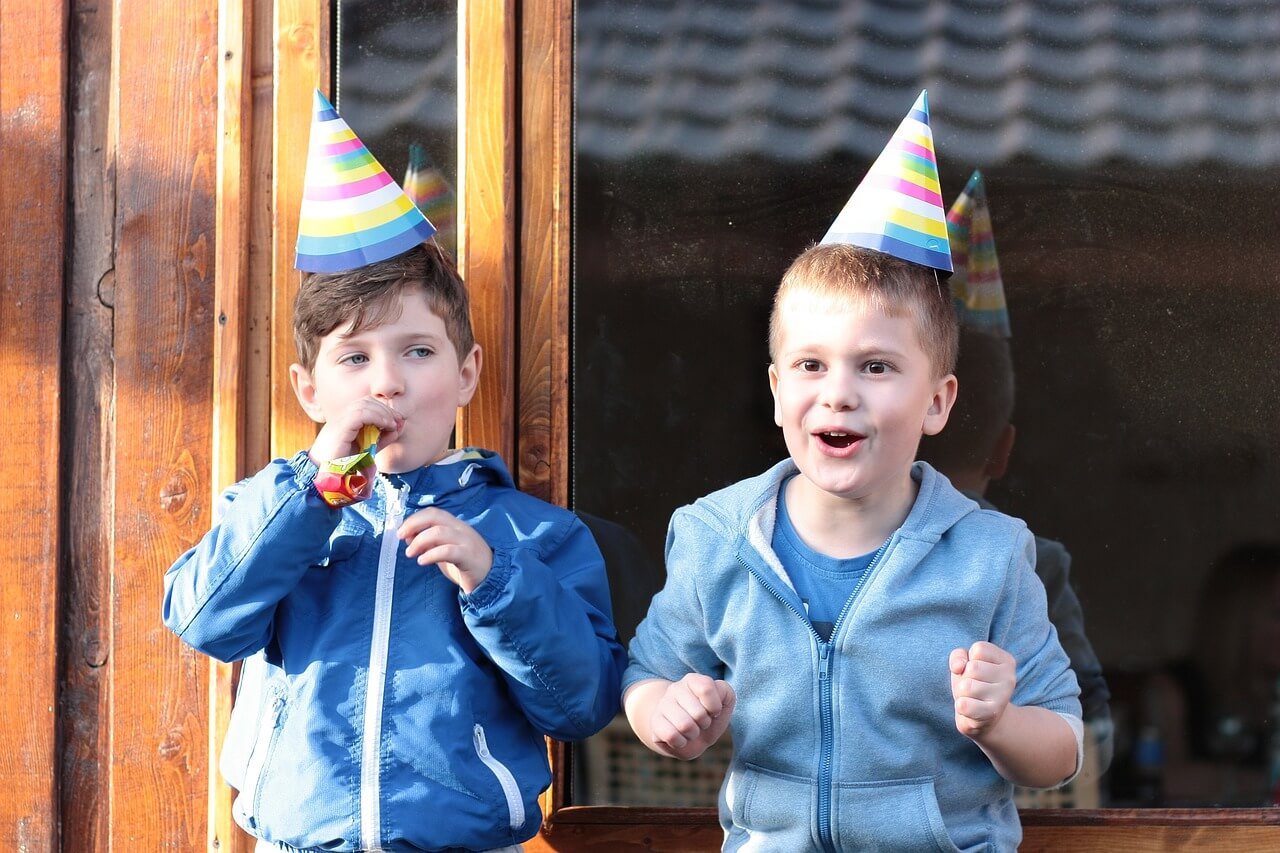 Two kids with party hats on and excited faces.